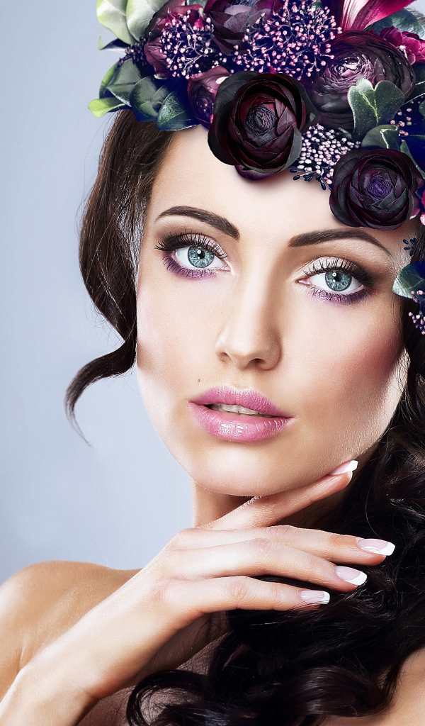 Красивая голубоглазая девушка с венком на голове на сером фоне