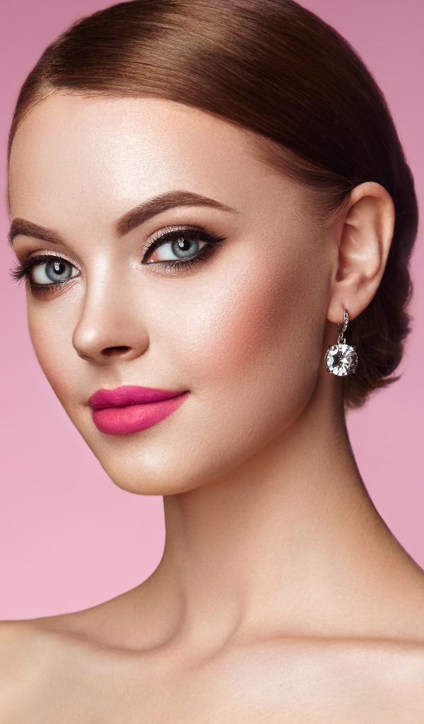 Красивая голубоглазая девушка с красивыми серьгами на розовом фоне