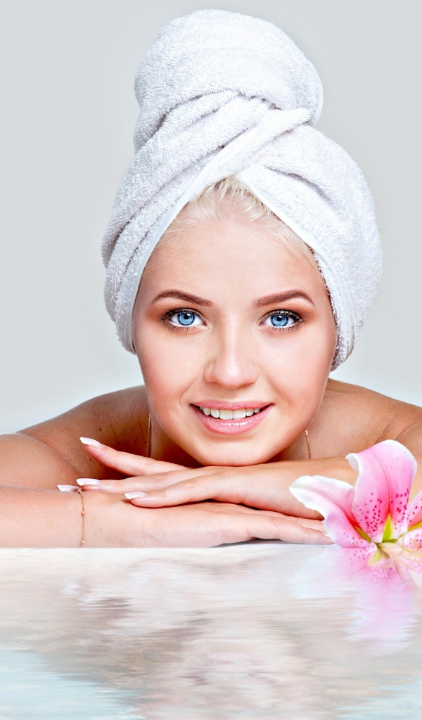 Красивая голубоглазая женщина в тюрбане с полотенца расслабляется в SPA