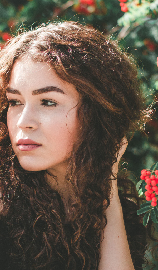 Красивая шатенка у ветки с красными ягодами рябины