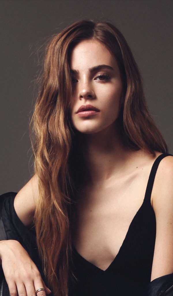 Красивая брюнетка в черном платье сидит на стуле