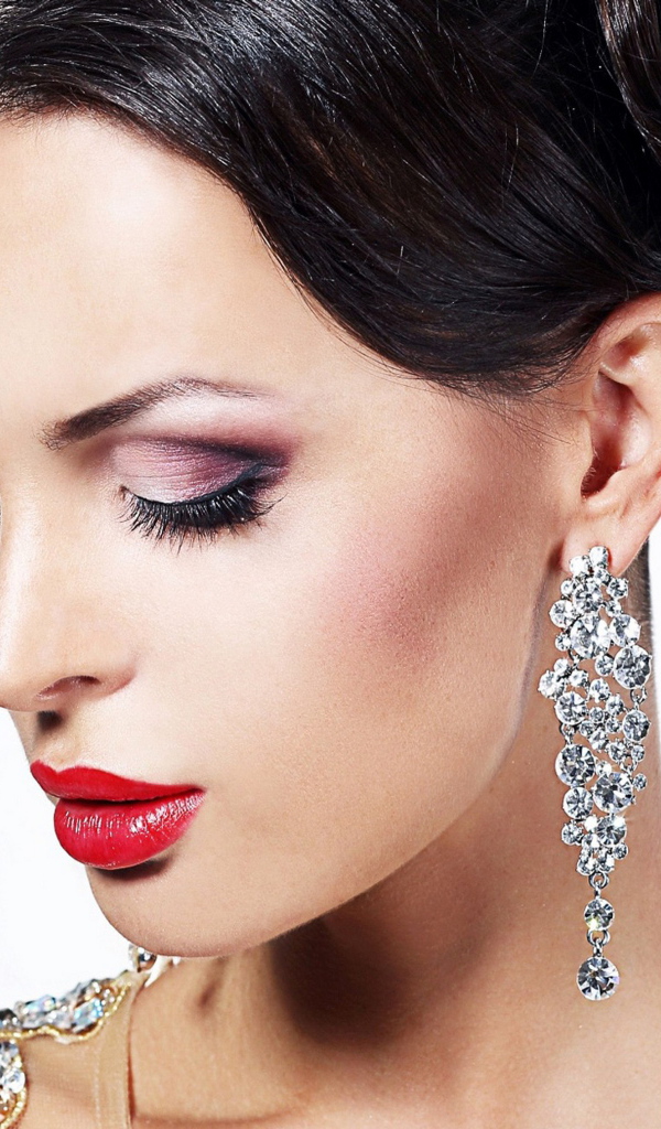 Красивая брюнетка в дорогих украшениях на белом фоне