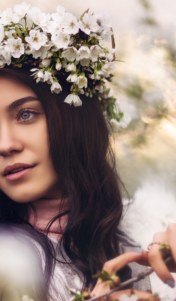 Красивая брюнетка с венком из цветов вишни на голове