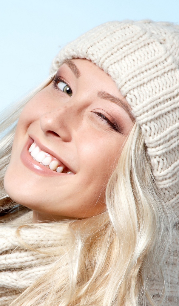 Красивая веселая блондинка в теплой шапке зимой