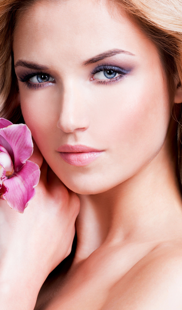 Красивая нежная блондинка с цветком орхидеи на белом фоне