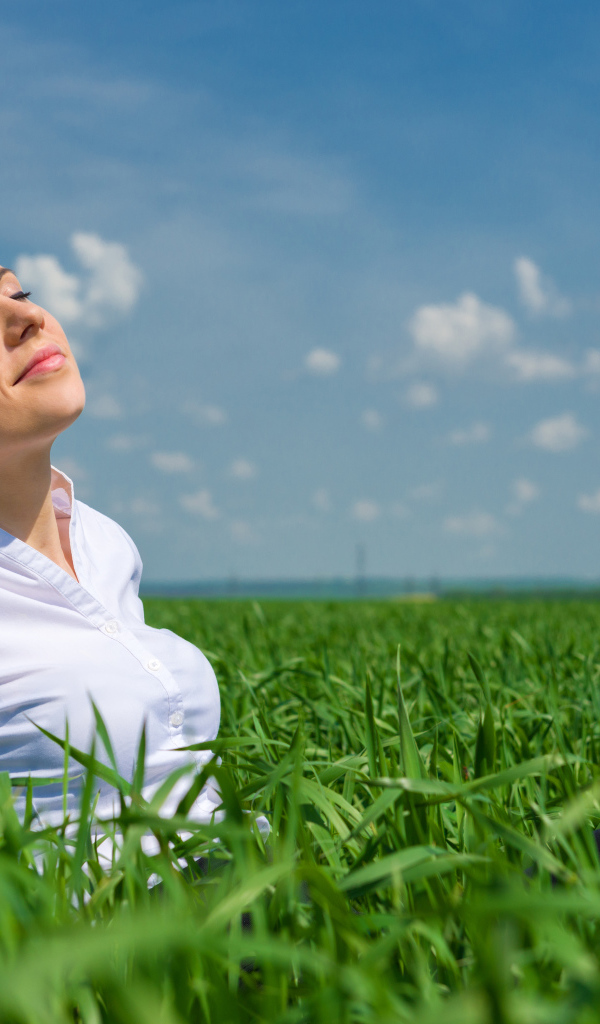 Красивая девушка нежится на солнце в зеленой траве