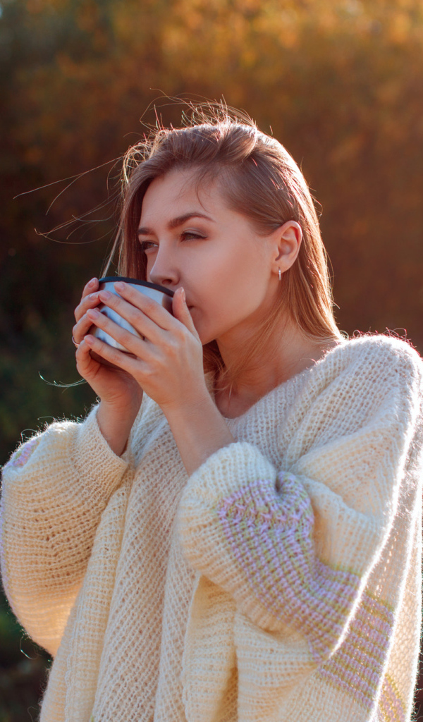 Красивая девушка пьет чай в теплом свитере