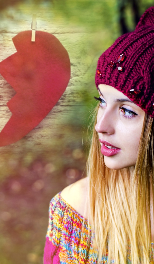 Красивая девушка в вязаной шапке на фоне разбитого сердца