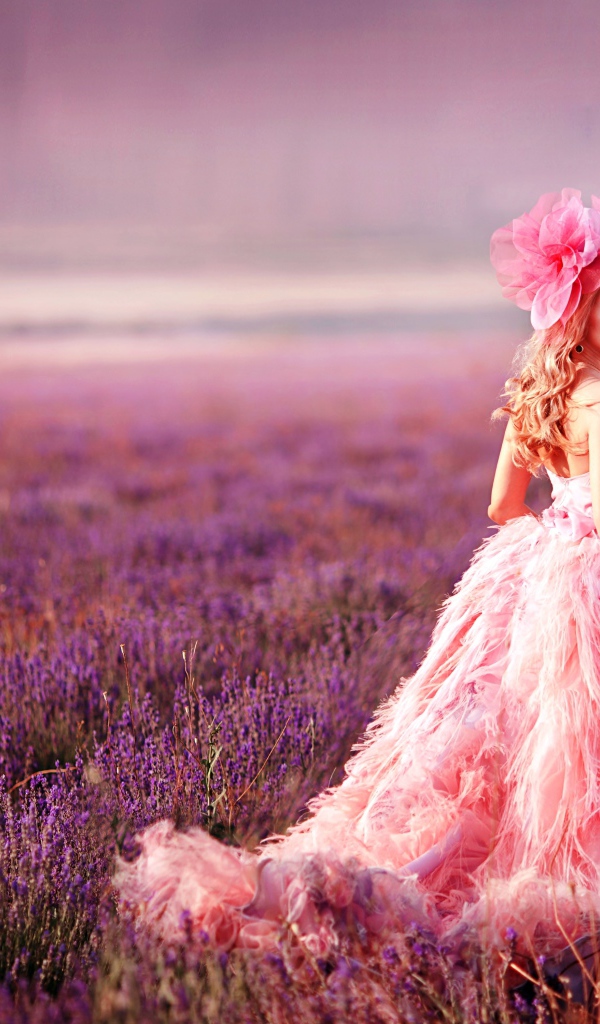 Красивая девушка в розовом платье гуляет по лавандовому полю