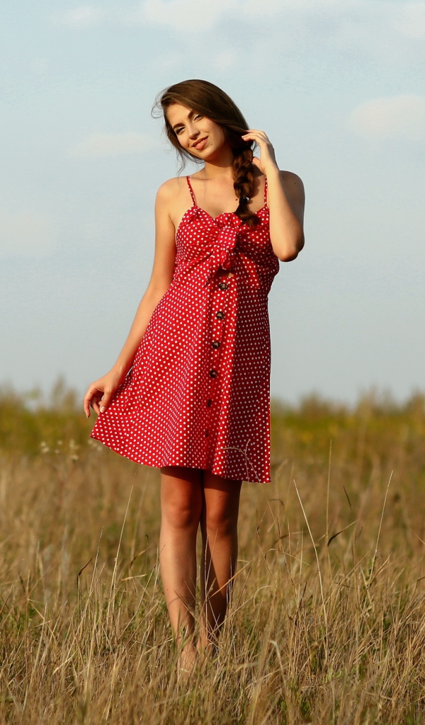 Красивая девушка в красном сарафане на поле 