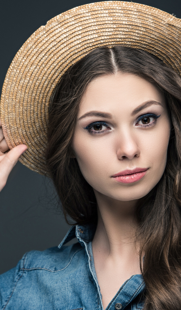 Красивая девушка в соломенной шляпе на сером фоне
