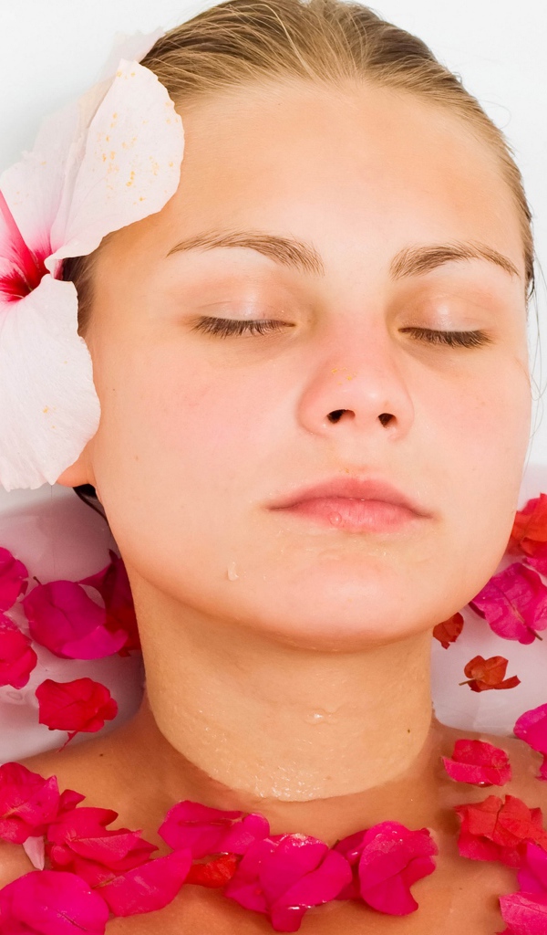 Красивая девушка в ванной с лепестками розы 