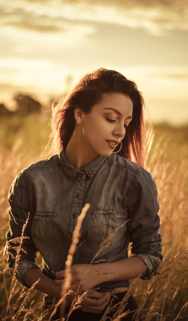 Красивая девушка на поле с колосками на фоне солнца