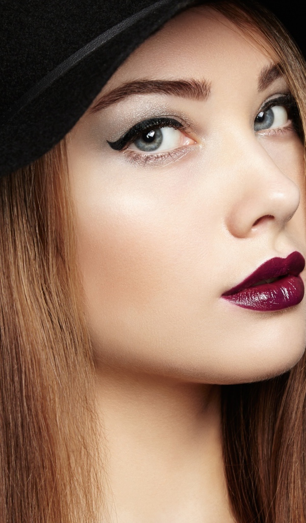 Красивая девушка с ярким макияжем в большой черной шляпе