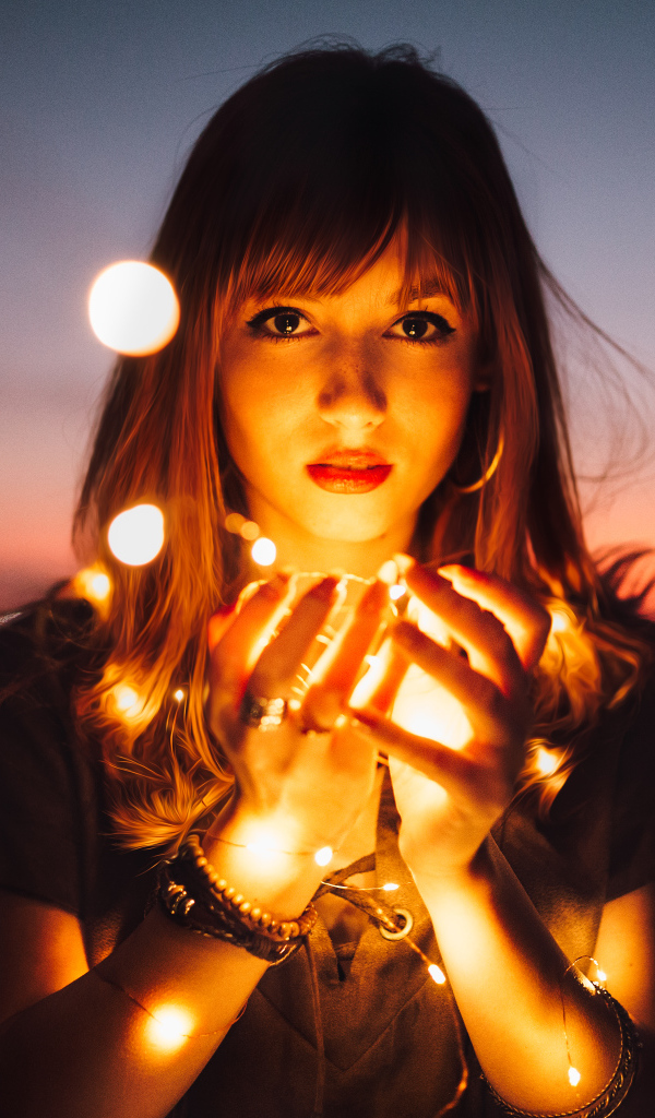 Красивая девушка с включенной гирляндой в руках 