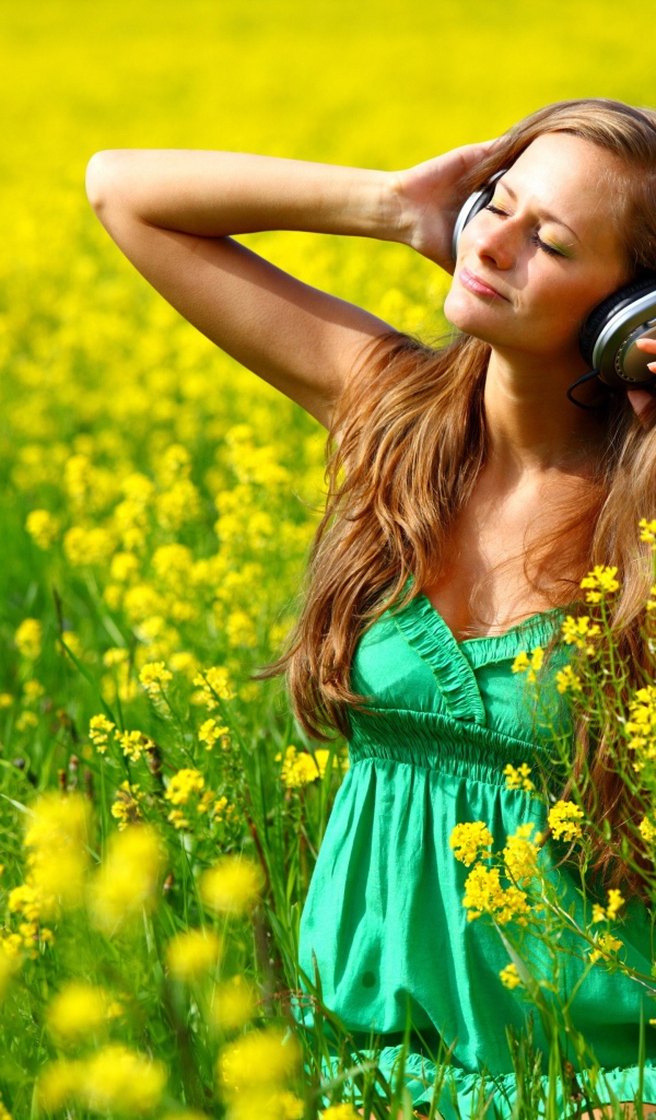 Красивая девушка в наушниках среди желтых цветов