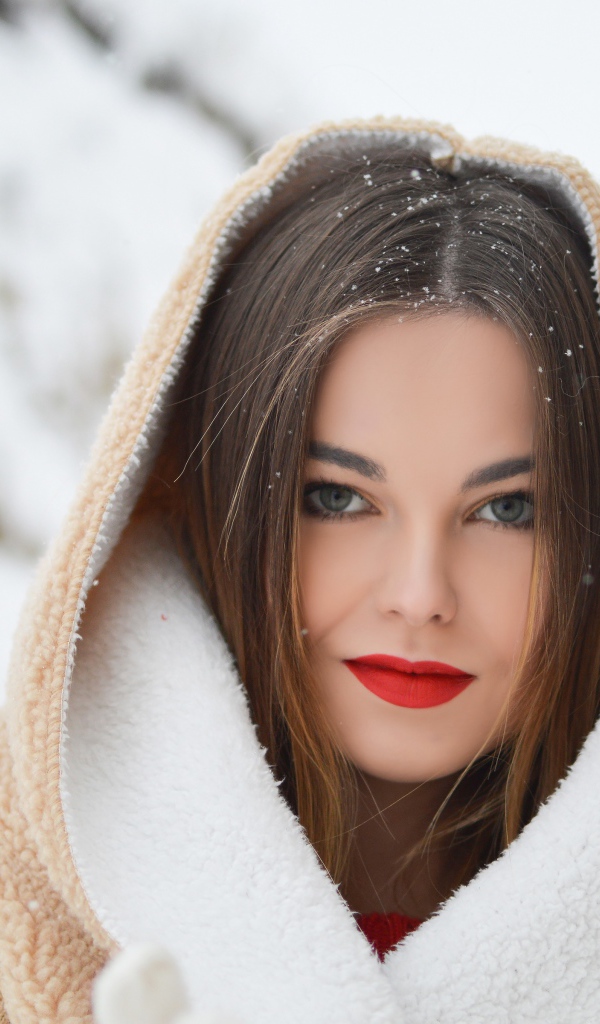 Красивая девушка с красными губами в теплой куртке зимой