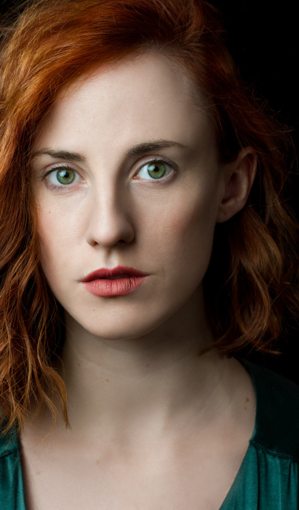 Красивая зеленоглазая рыжеволосая девушка на черном фоне 