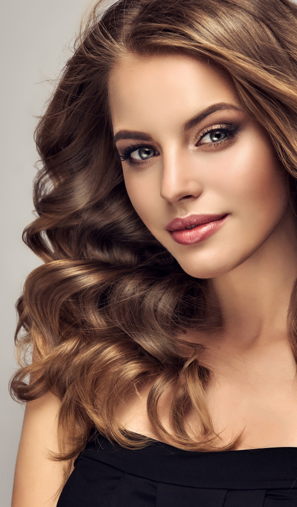 Красивая длинноволосая шатенка на сером фоне