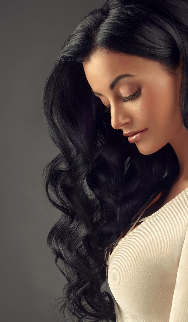 Красивая длинноволосая брюнетка на сером фоне