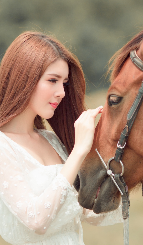 Красивая длинноволосая азиатка гладит лошадь