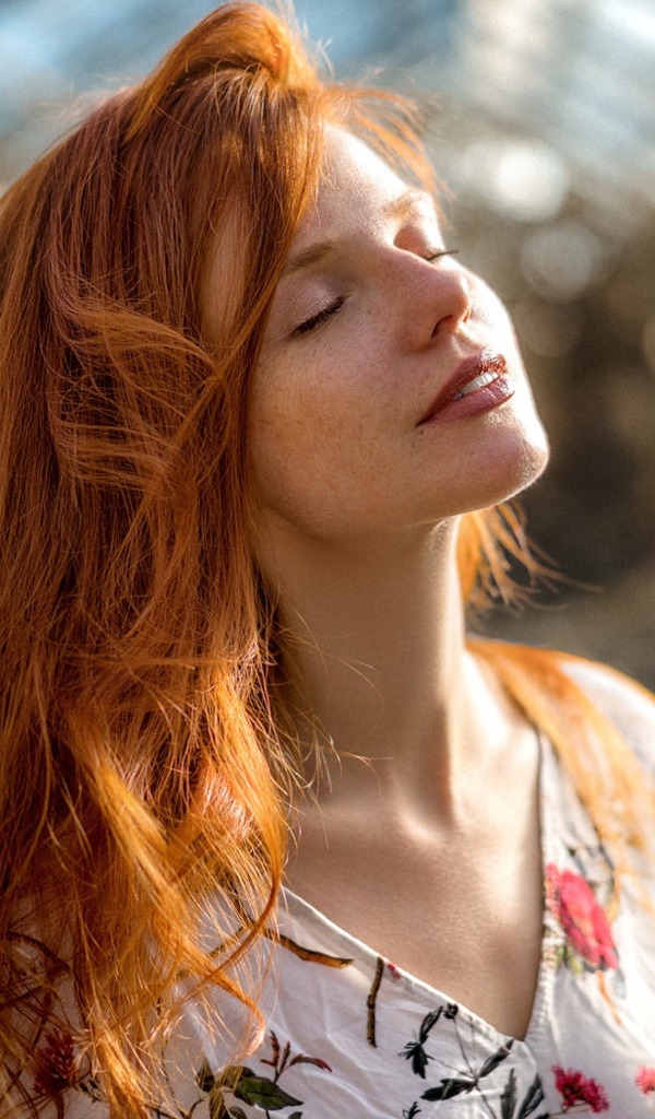 Красивая рыжеволосая девушка нежится в лучах солнца