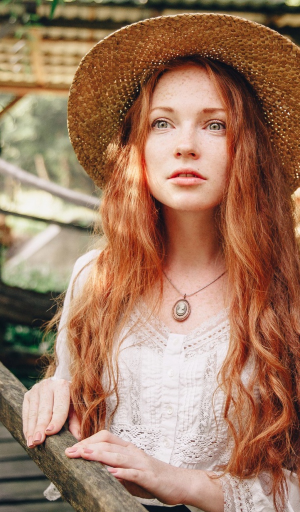 Красивая рыжеволосая девушка в соломенной шляпе