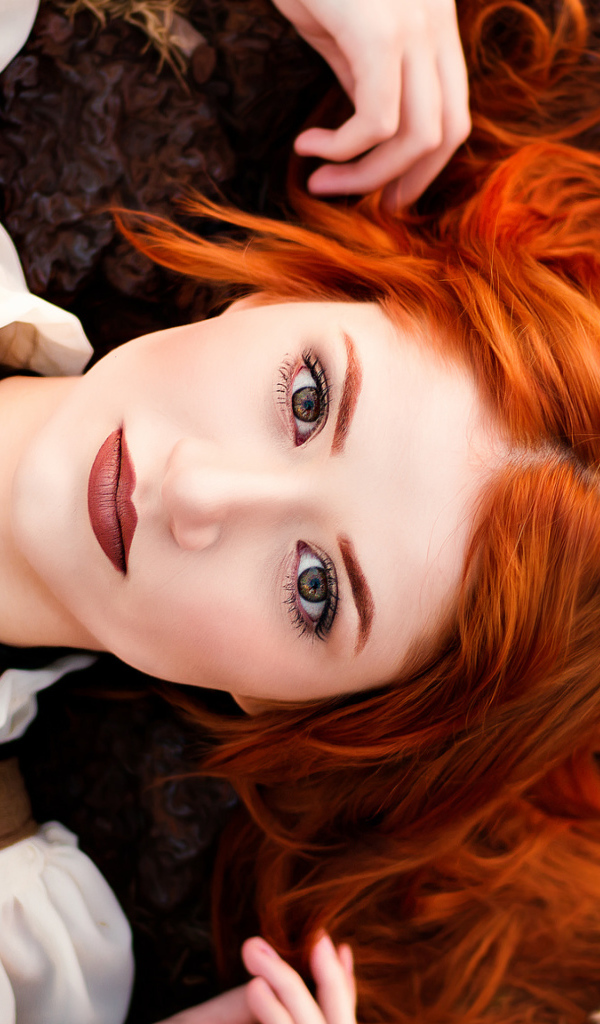 Красивая рыжеволосая девушка лежит на земле 