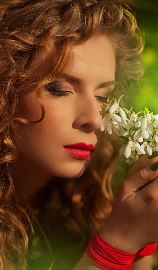 Красивая рыжеволосая девушка с букетом подснежников в руках