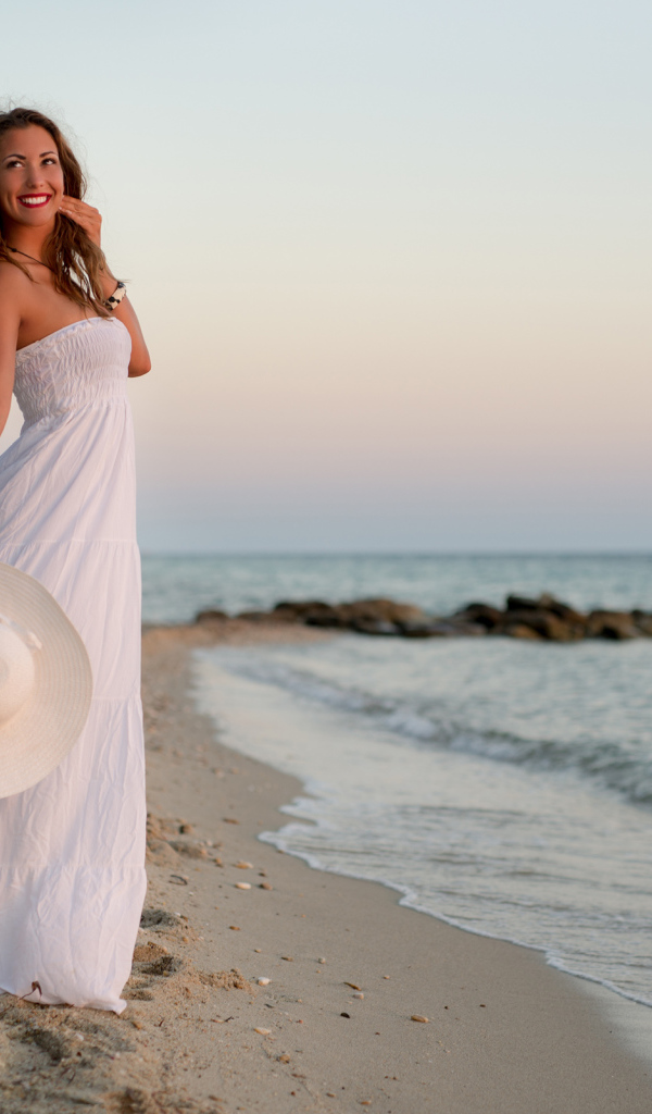 Красивая улыбающаяся девушка в белом платье на побережье