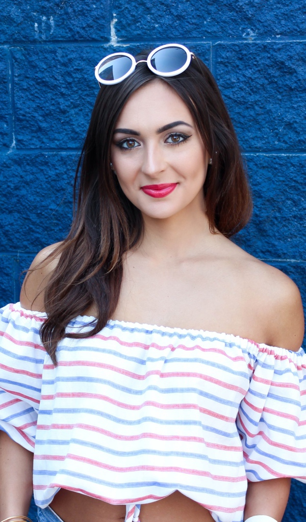 Красивая улыбающаяся девушка на фоне синей стены