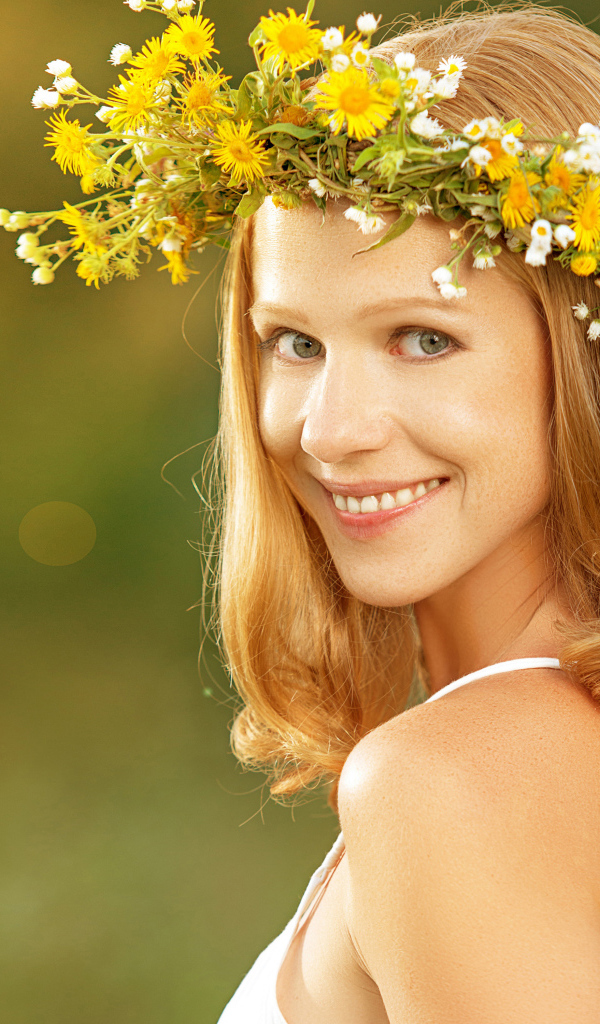 Красивая улыбающаяся девушка с венком из полевых цветов на голове