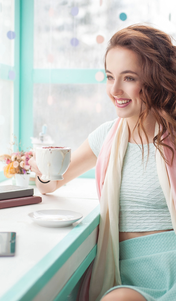 Красивая улыбающаяся девушка шатенка с чашкой кофе