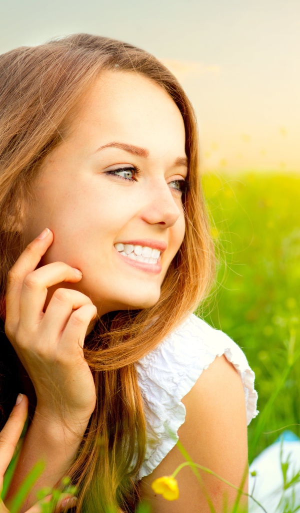 Красивая улыбающаяся молодая девушка лежит в зеленой траве