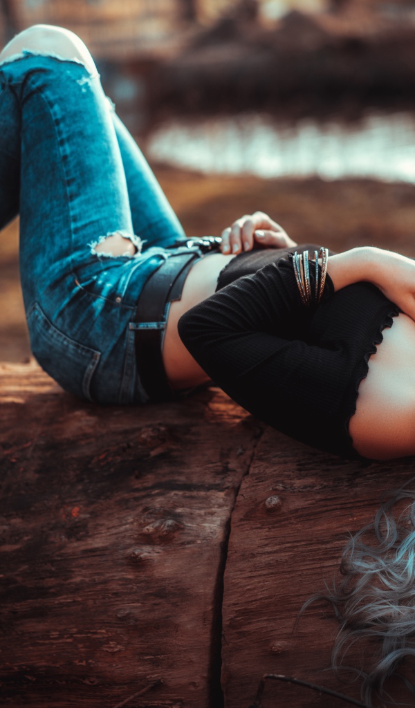 Красивая молодая блондинка лежит на сухом дереве