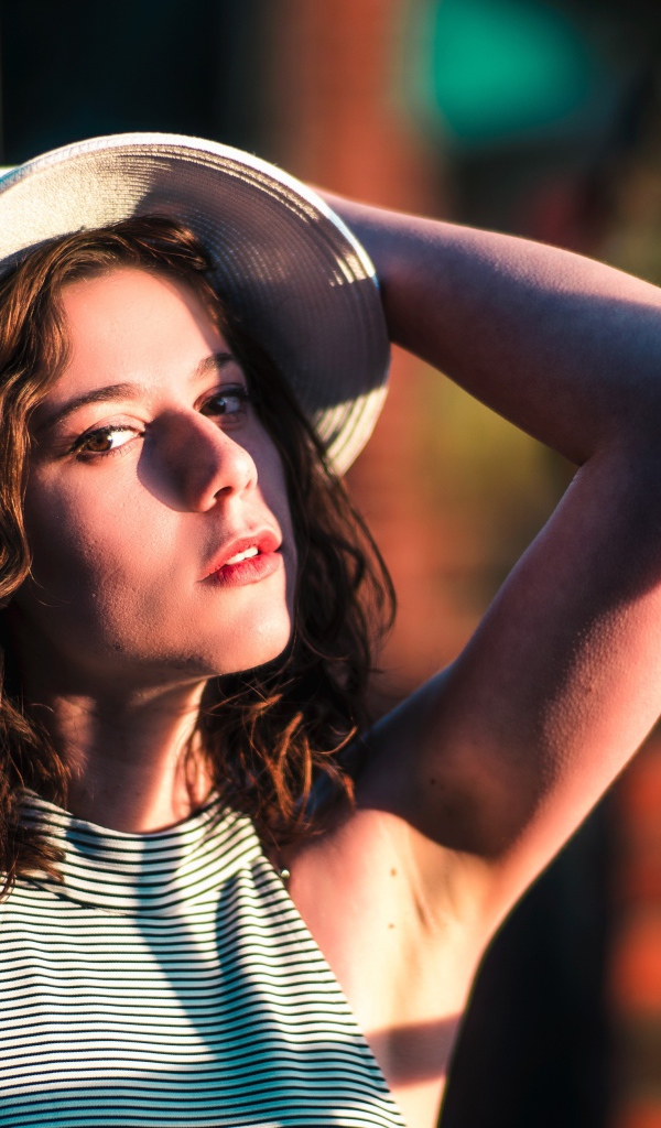 Красивая молодая девушка в белой шляпе в свете солнца