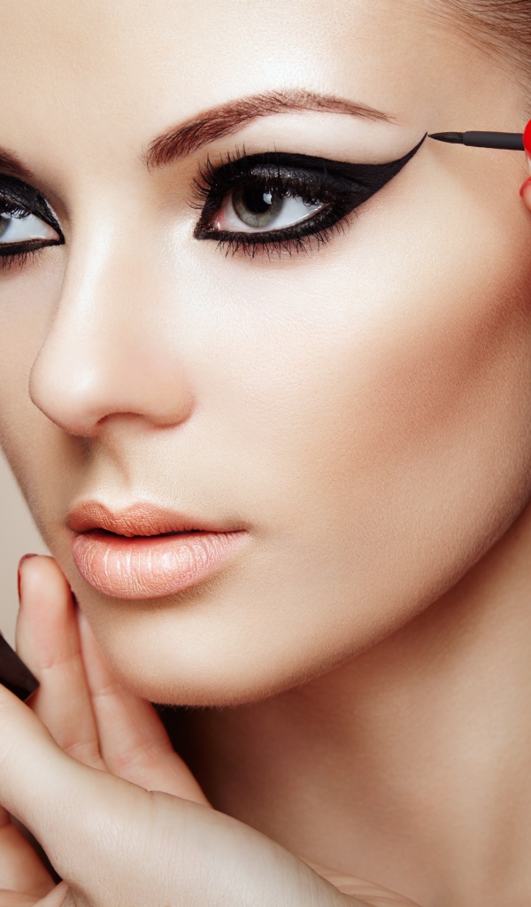 Красивой молодой девушке модели делают макияж глаз