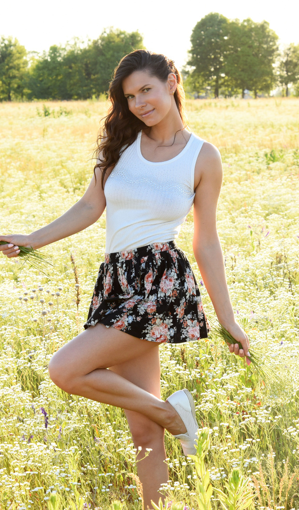 Красивая молодая девушка на поле с белыми ромашками