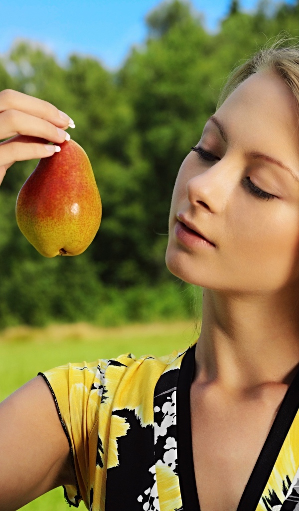 Красивая молодая девушка с грушей в руках