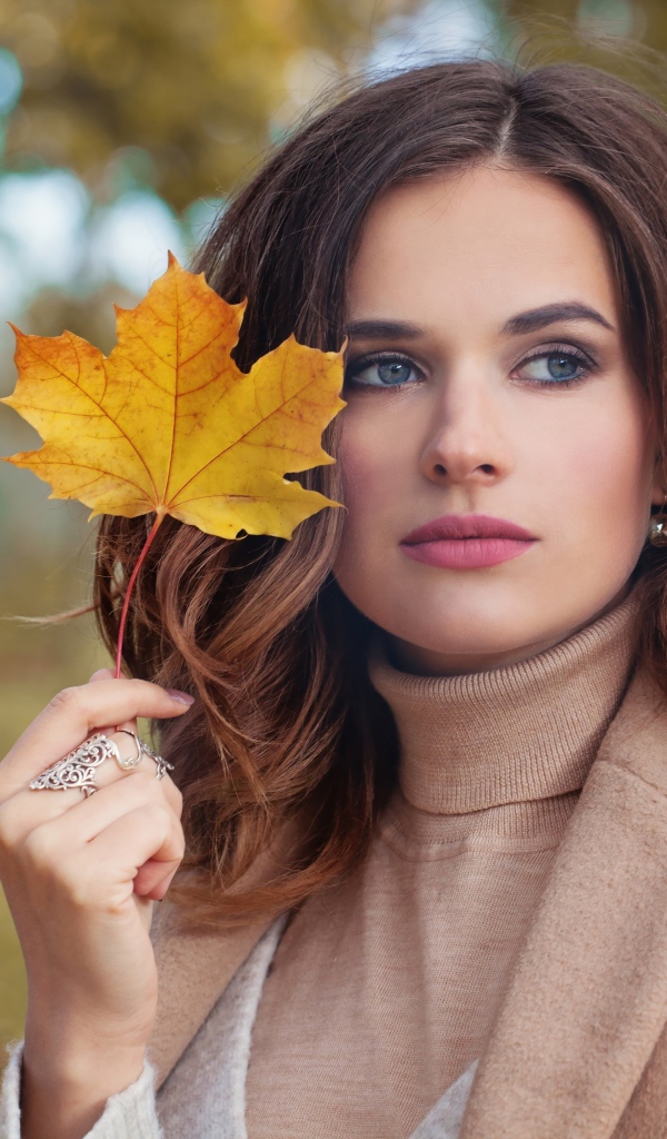 Красивая молодая девушка шатенка с желтым листом в руке