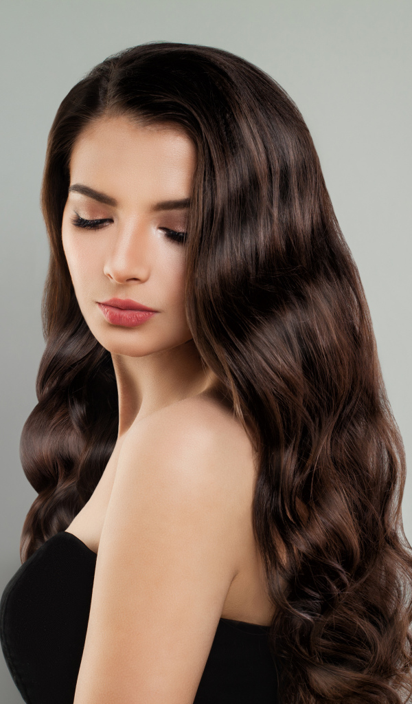 Красивая молодая длинноволосая девушка брюнетка на сером фоне