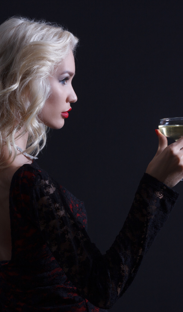 Блондинка с бокалом мартини в руках сером фоне 