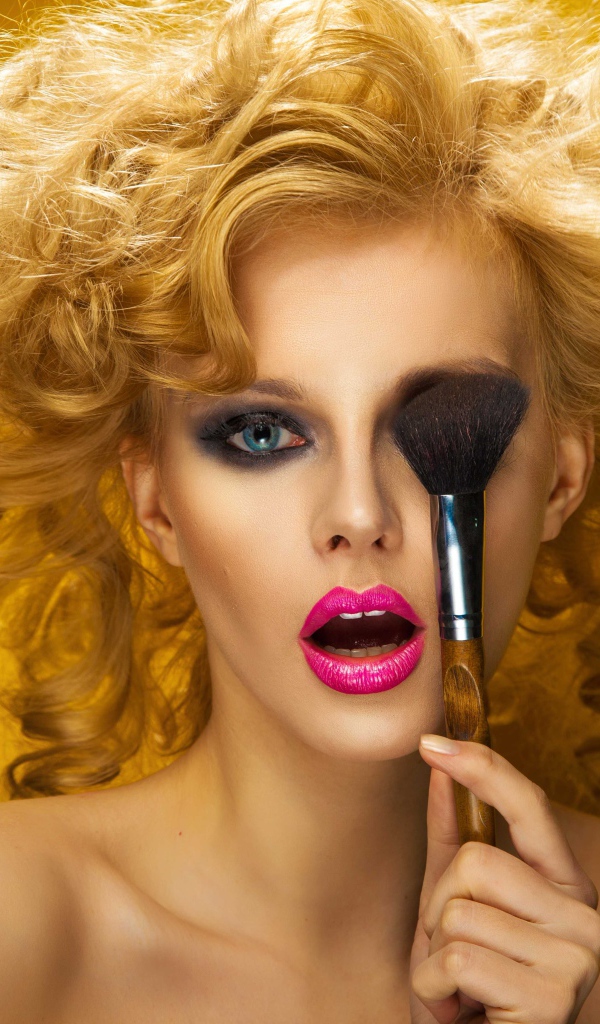 Блондинка с ярким макияжем с кистью у лица