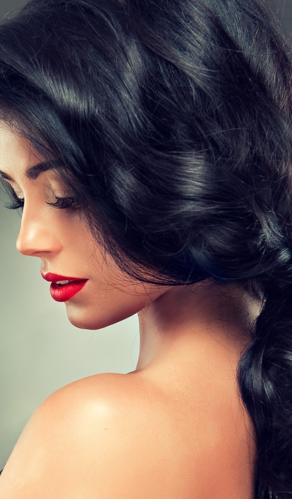 Девушка брюнетка с красивыми волосами на сером фоне