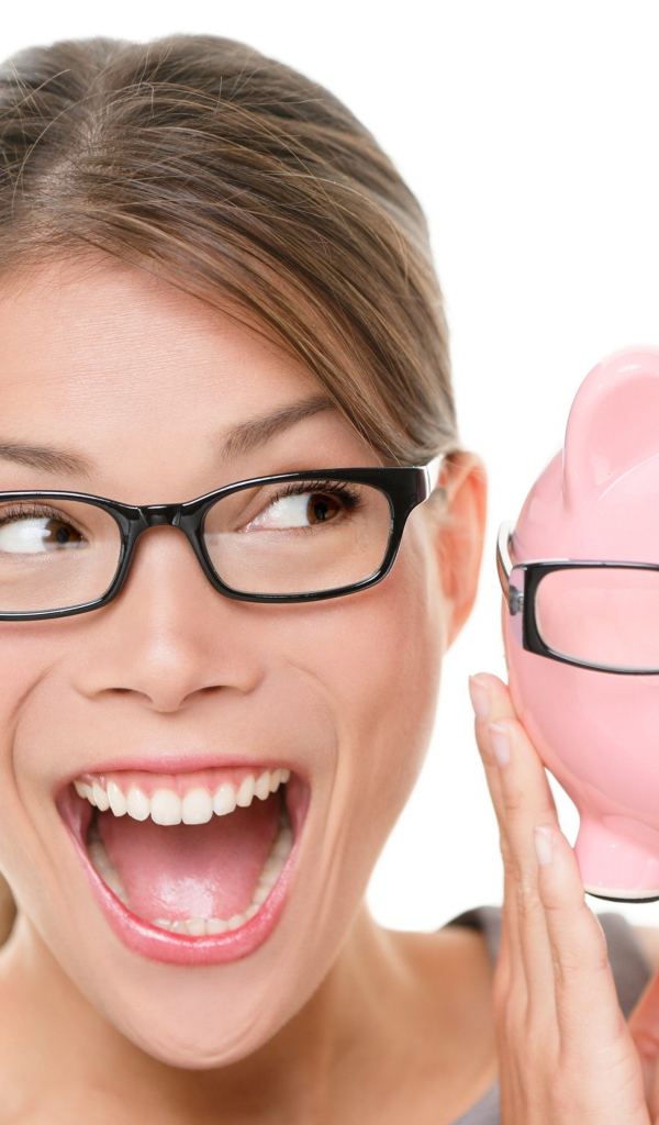 Веселая девушка в очках с копилкой в руках на белом фоне