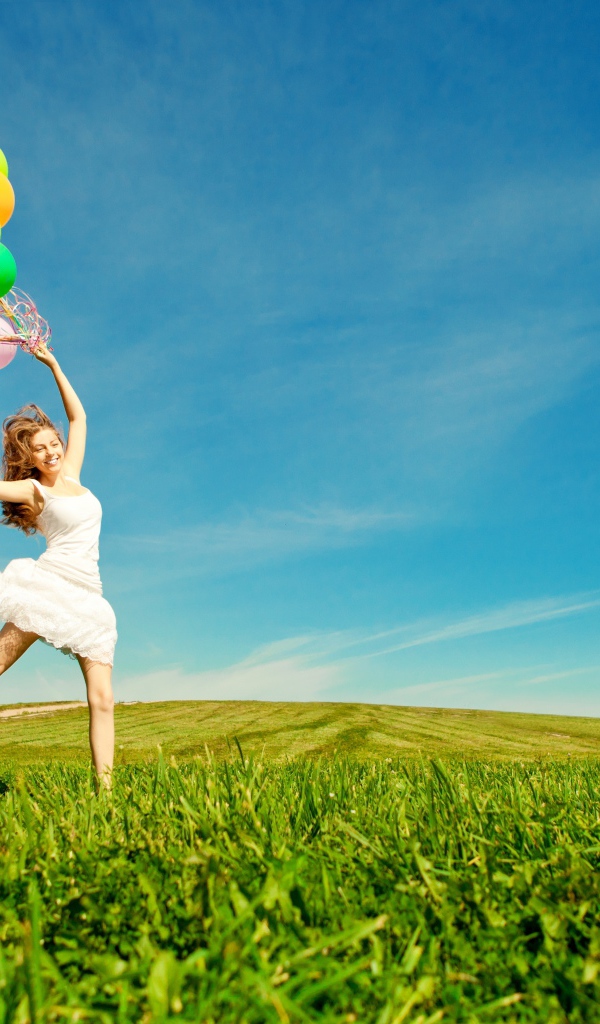 Веселая девушка в белом платье с разноцветными воздушными шариками