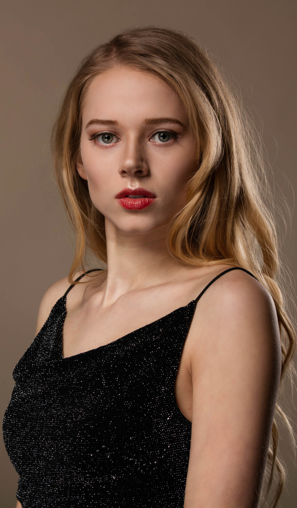 Нежная девушка модель в черном платье на сером фоне