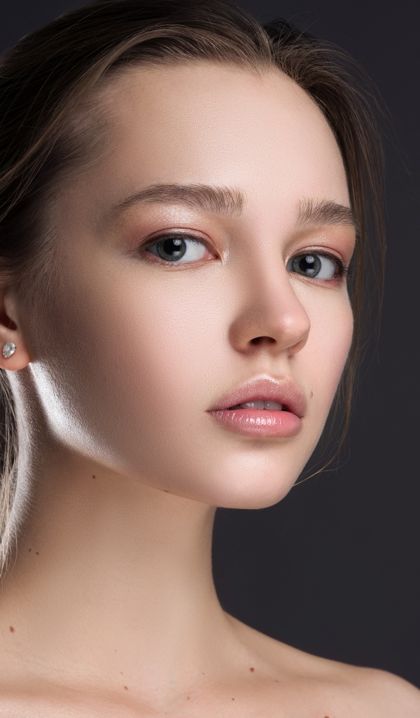 Нежная настоящая девушка шатенка на сером фоне