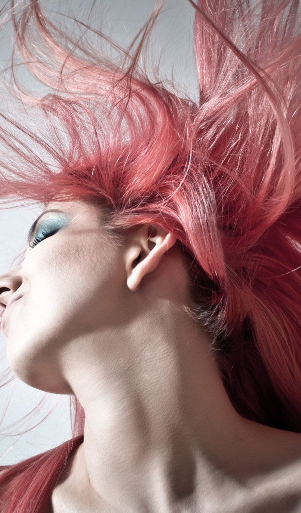Девушка с распущенными розовыми волосами на сером фоне
