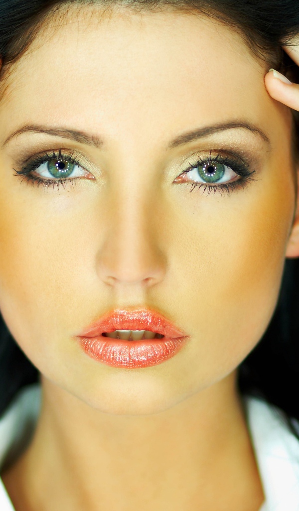 Зеленоглазая брюнетка держится руками за голову